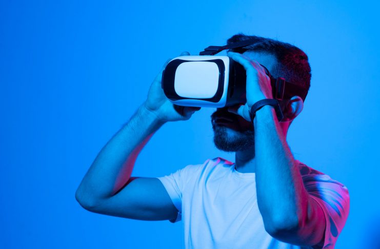 Portraite of young man gamer using virtual reality headset and playing favourite video games with a friends in metaverse. VR, future, gadgets, technology, education online, studying