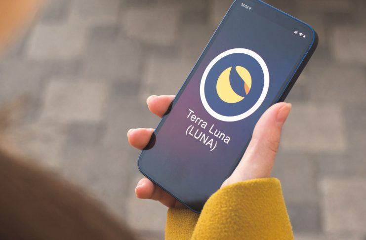 Terra Luna cryptocurrency symbol, logo. Business and financial concept. Hand with smartphone, screen with crypto icon closeup